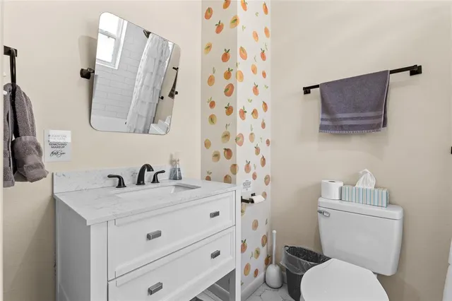 a bathroom with a granite countertop toilet sink and mirror