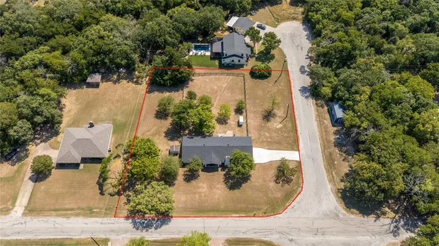 an aerial view of a house with a yard and large trees