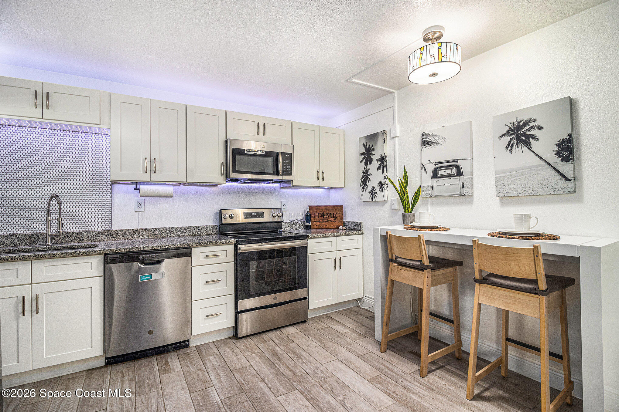 7605 Ridgewood Avenue, Unit 3 Cape Canaveral, FL 32920 - Photo 3 of 28 a kitchen with granite countertop a sink cabinets and stainless steel appliances