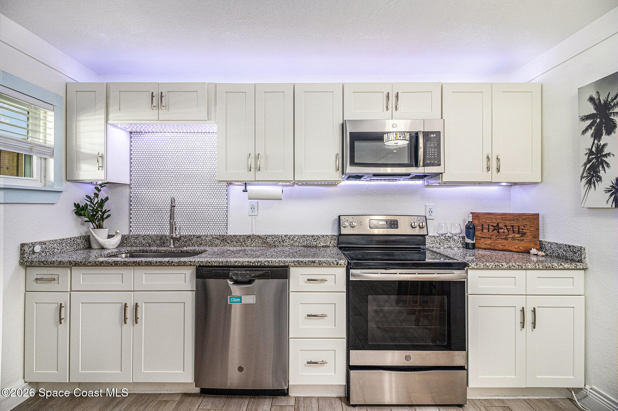 7605 Ridgewood Avenue, Unit 3 Cape Canaveral, FL 32920 - Photo 6 of 28 a kitchen with granite countertop a stove sink and cabinets