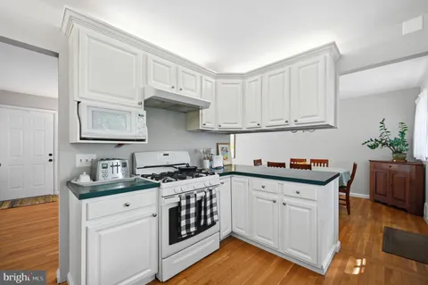 a kitchen with stainless steel appliances granite countertop a stove a sink and white cabinets