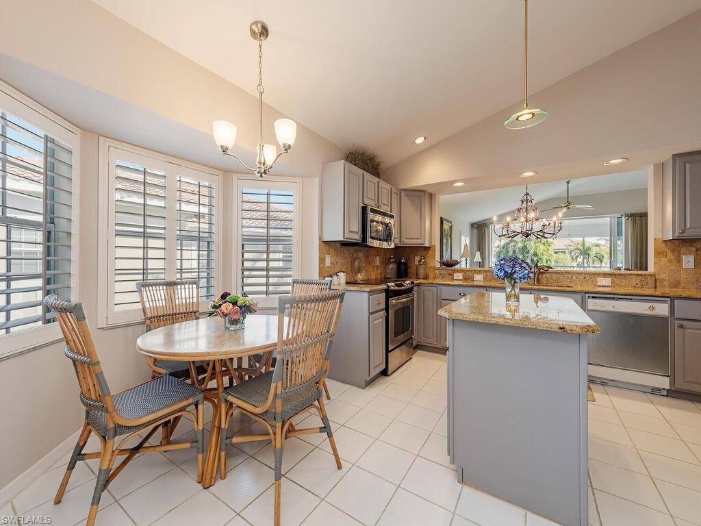 3572 Windjammer Circle, Unit 1404 Naples, FL 34112 - Photo 5 of 17 a kitchen with stainless steel appliances kitchen island granite countertop a sink and cabinets