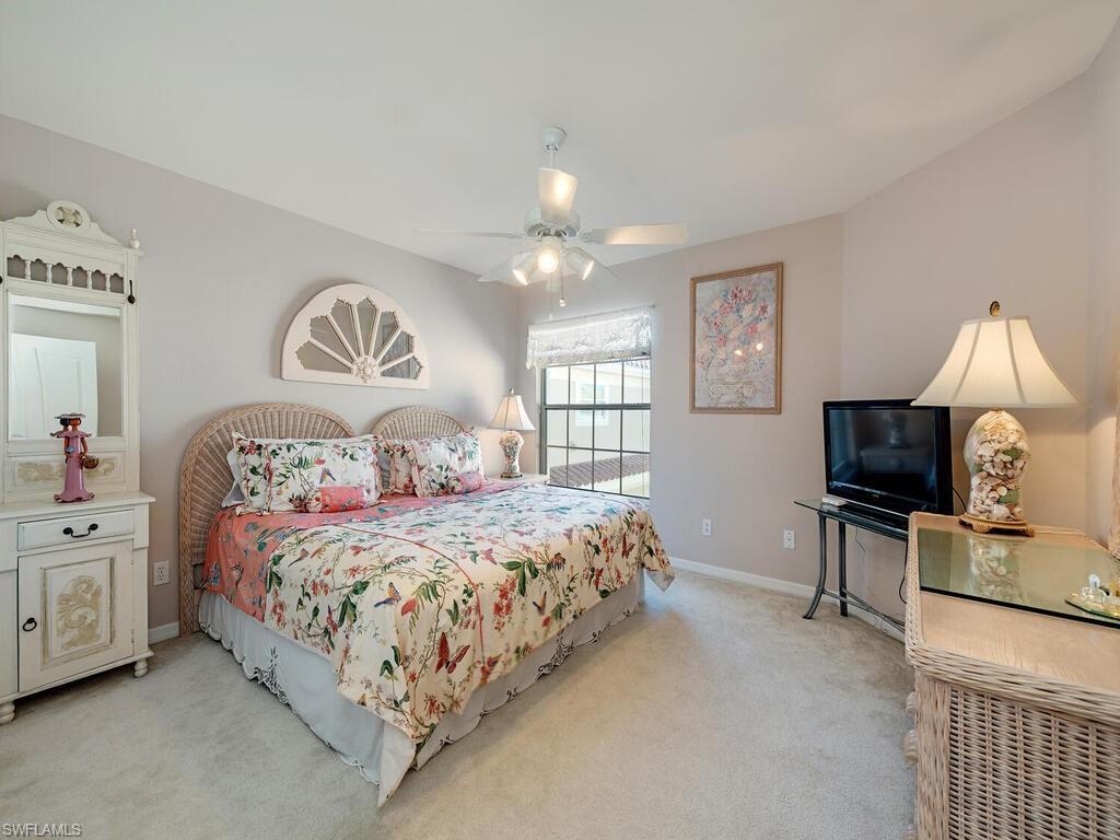 3572 Windjammer Circle, Unit 1404 Naples, FL 34112 - Photo 10 of 17 a bedroom with a bed and a chandelier