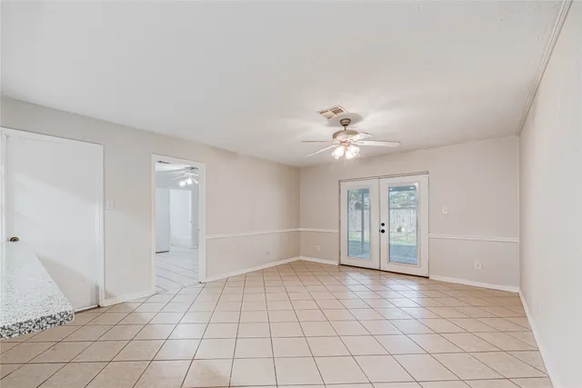 a view of an empty room with window and chandelier fan