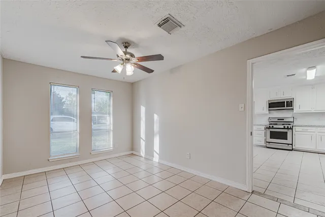 a view of an empty room with a ceiling fan and window