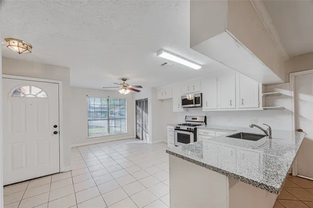 a kitchen with granite countertop a sink cabinets and stainless steel appliances