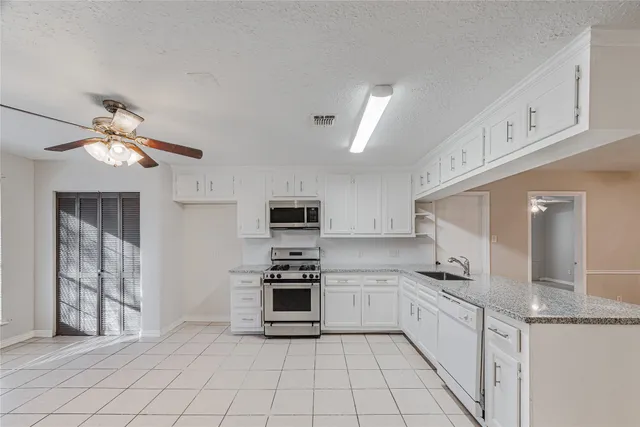 a kitchen with granite countertop a sink cabinets and stainless steel appliances