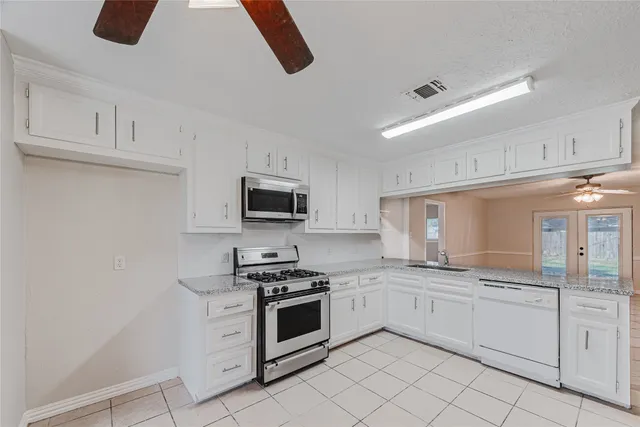 a kitchen with white cabinets and appliances