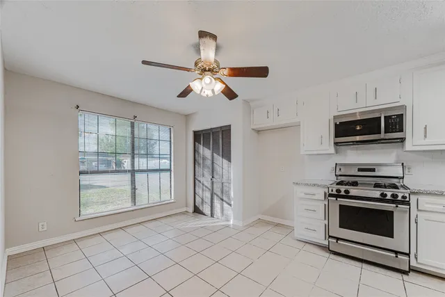 a kitchen with stainless steel appliances a stove a microwave and white cabinets