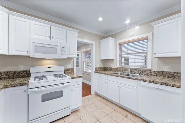 a kitchen with granite countertop white cabinets and white appliances