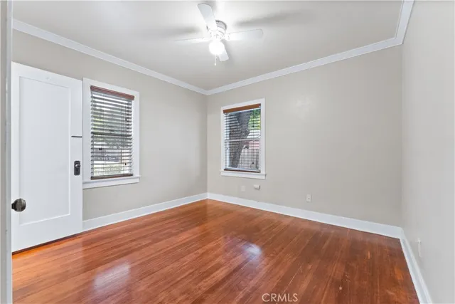 a view of an empty room with wooden floor and a window