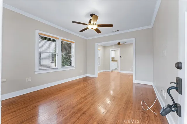 a view of empty room with wooden floor and fan