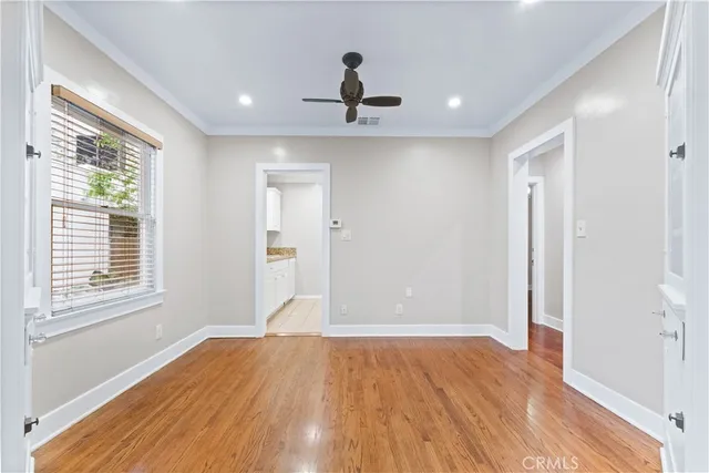 a view of empty room with wooden floor and fan