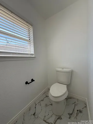 a white toilet sitting in a bathroom next to a window