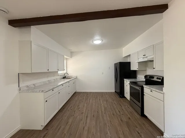 a kitchen with a sink a stove top oven and wooden floor