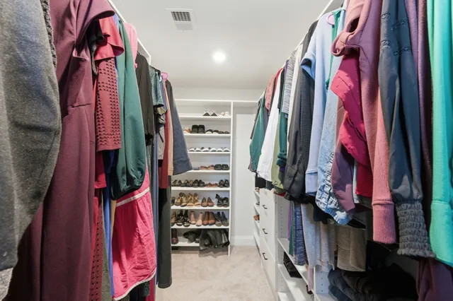 a view of walk in closet with clothes and shoes