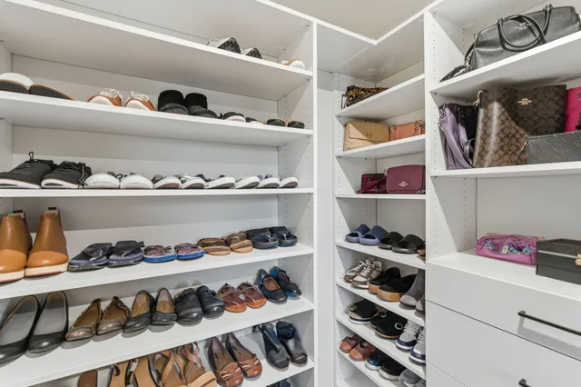 a view of walk in closet with clothes and shoes