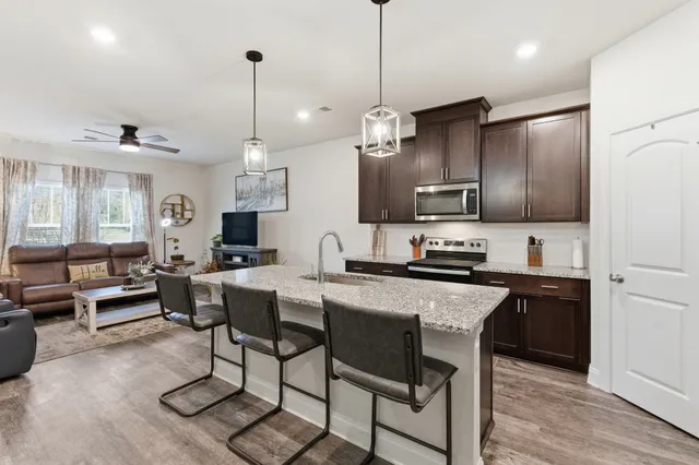 a kitchen with stainless steel appliances granite countertop a stove top oven a refrigerator a sink and a center island