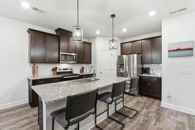 a kitchen with stainless steel appliances granite countertop a refrigerator a stove a sink a microwave and a refrigerator