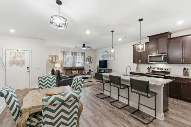 a kitchen with stainless steel appliances granite countertop a stove a sink dishwasher a dining table and chairs with wooden floor