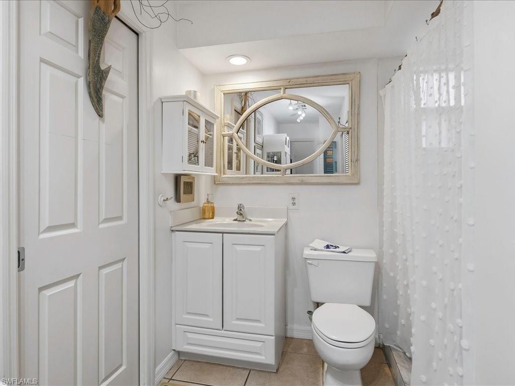1337 Solana Road Naples, FL 34103 - Photo 14 of 23 Bathroom featuring a white vanity with integrated sink, a built-in wall cabinet, a toilet, and tiled flooring