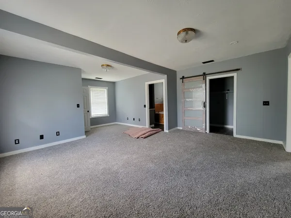 a view of an empty room with window and closet area