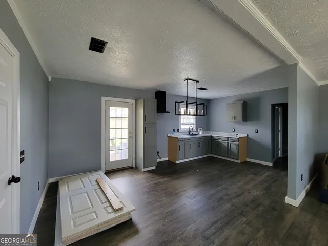 a living room with stainless steel appliances furniture and a kitchen view