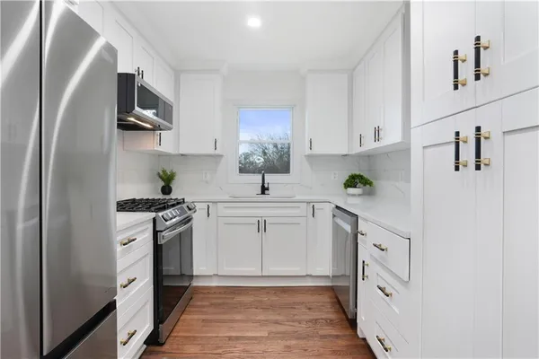 a kitchen with white cabinets stainless steel appliances and a sink