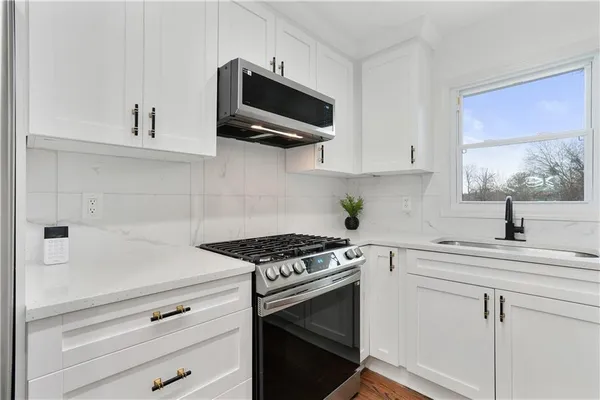 a kitchen with white cabinets stainless steel appliances and sink