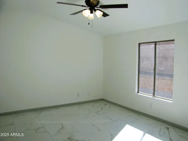 an empty room with a window and a fan