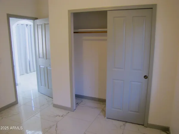 a view of an empty room with closet and mirror