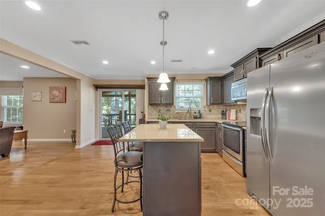a kitchen with a dining table chairs wooden floor cabinets and stainless steel appliances