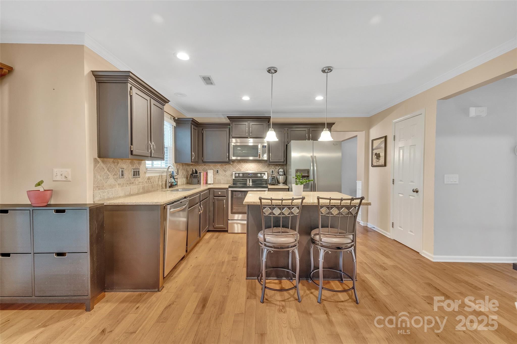 12351 Cardinal Point Road Charlotte, NC 28269 - Photo 13 of 43 a kitchen with a dining table chairs wooden floor cabinets and stainless steel appliances