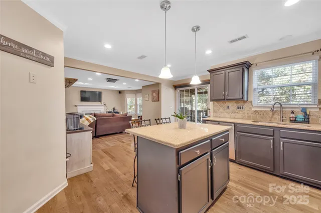 a kitchen with stainless steel appliances granite countertop a refrigerator a stove a sink a dining table and chairs with wooden floor