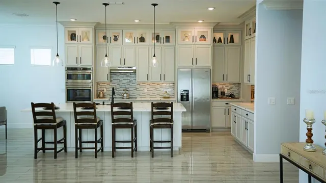 a kitchen with stainless steel appliances a sink a stove a refrigerator cabinets and a dining table