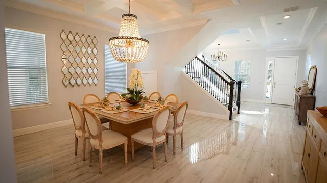 a view of a dining room with furniture a chandelier and wooden floor