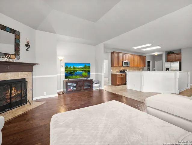 a living room with furniture and a fireplace with kitchen view