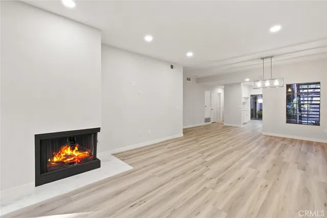 an empty room with wooden floor fireplace and windows