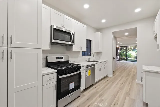 a kitchen with stainless steel appliances white cabinets and stove top oven