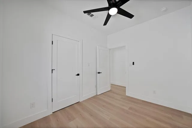 a view of a room with wooden floor and ceiling fan