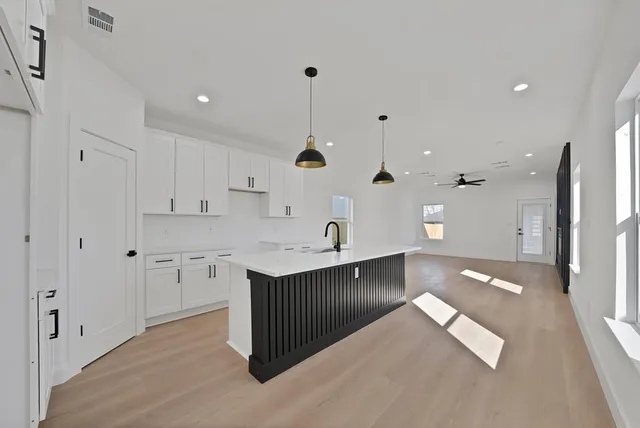 a large kitchen with stainless steel appliances kitchen island granite countertop a sink and dishwasher with white cabinets