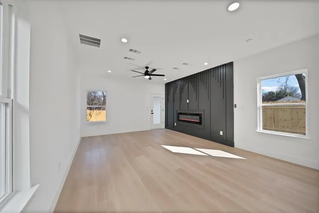 a view of an empty room with a window and wooden floor