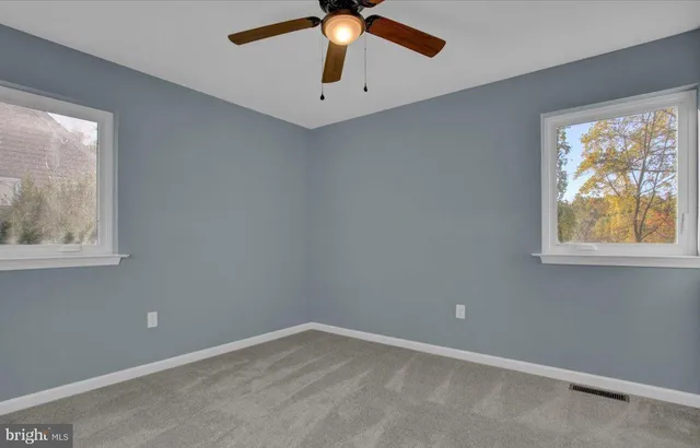 an empty room with windows and fan