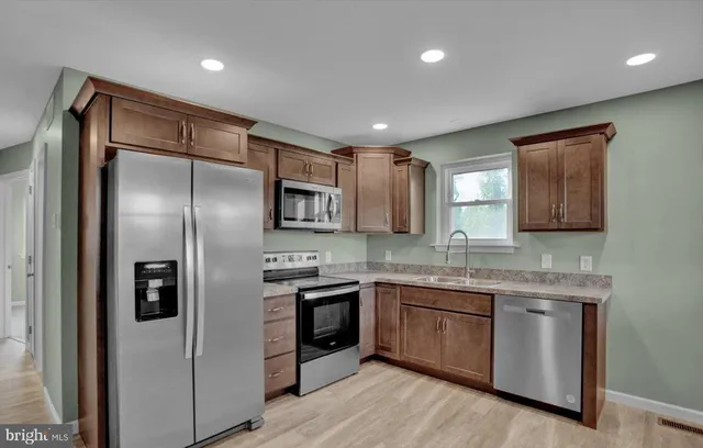 a kitchen with stainless steel appliances granite countertop a refrigerator a sink a stove and oven