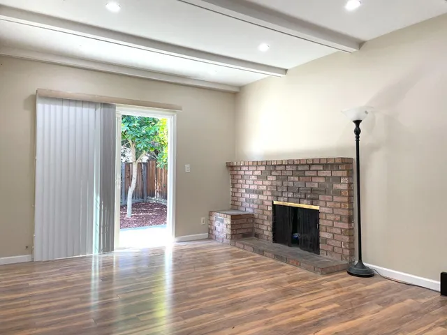 a view of empty room with wooden floor and fireplace