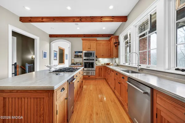 a large kitchen with stainless steel appliances a large counter top a stove a sink and a refrigerator