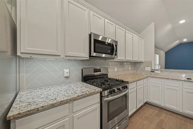 a kitchen with stainless steel appliances granite countertop a stove microwave and sink