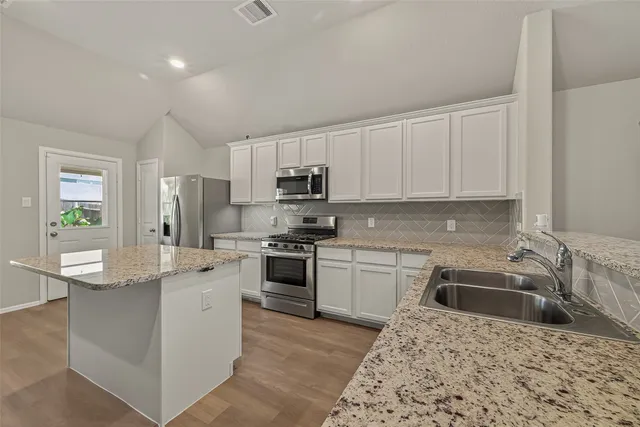 a kitchen with kitchen island granite countertop a stove sink and microwave
