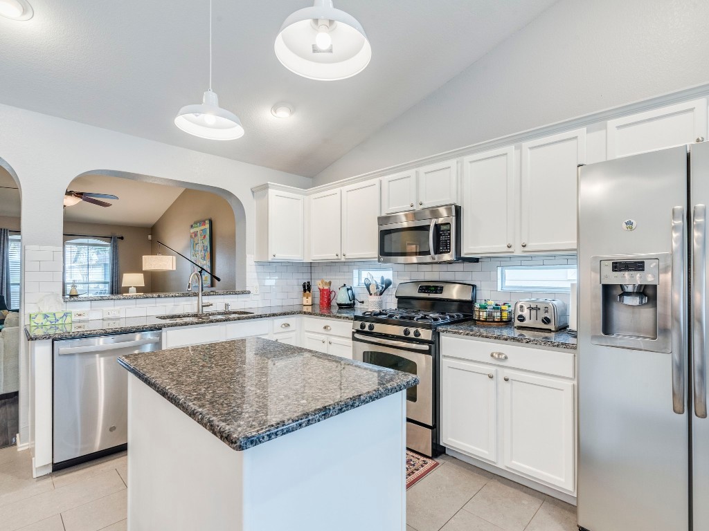 a kitchen with granite countertop stainless steel appliances a sink a stove top oven a counter space and cabinets