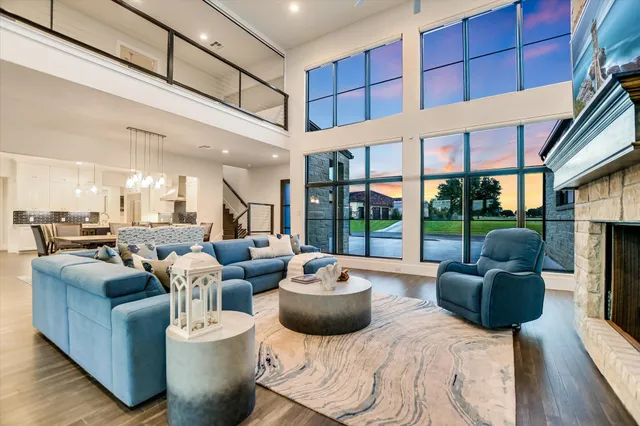 a living room with furniture large windows and wooden floor